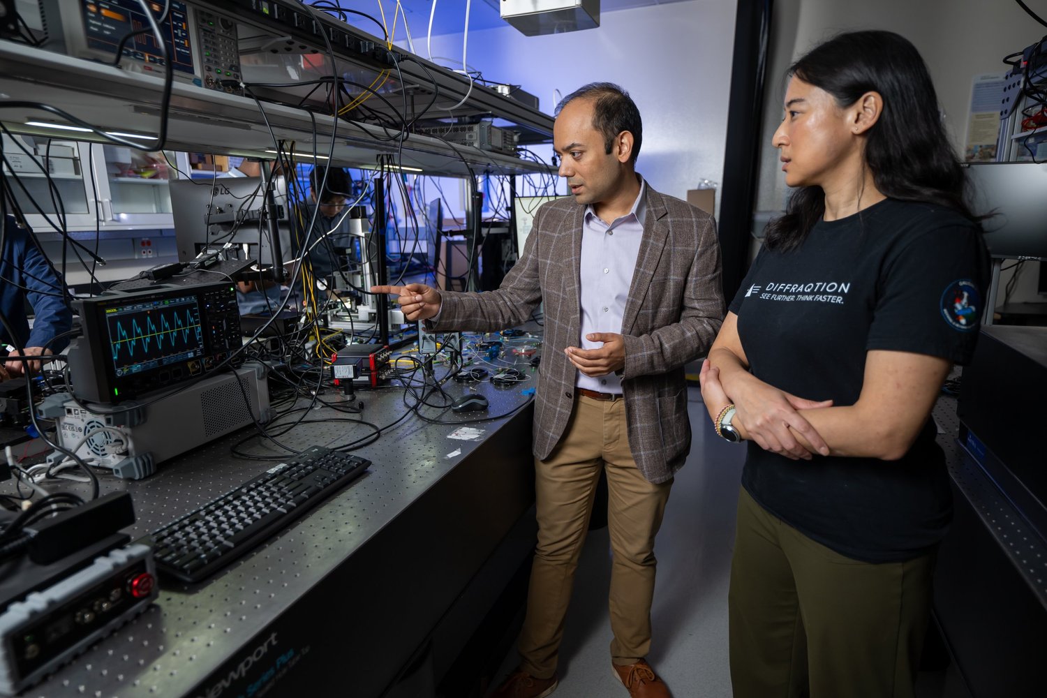 Three men working with electronic equipment, oscilloscopes, and monitors in a dark room, possibly conducting experiments or tests.